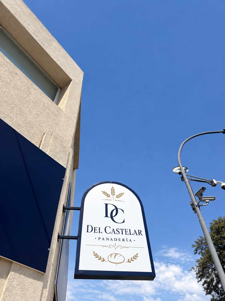 Cartel exterior de la panadería Del Castelar sobre el cielo azul